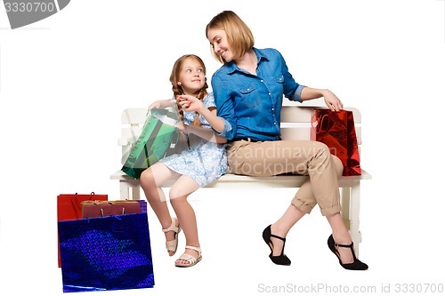 Image of Happy  mother and daughter with shopping bags sitting at studio 