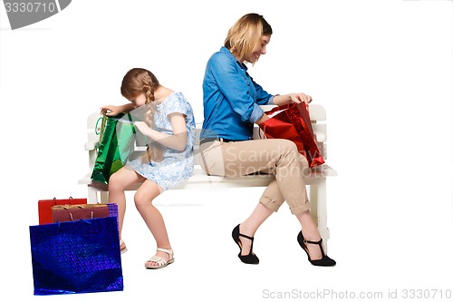 Image of Happy  mother and daughter with shopping bags sitting at studio 