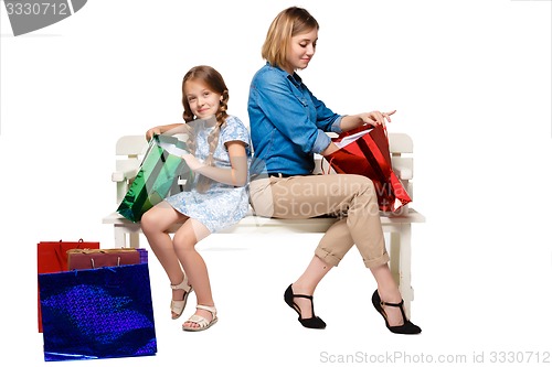 Image of Happy  mother and daughter with shopping bags sitting at studio 
