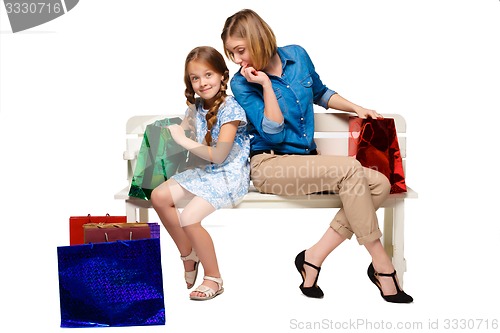 Image of Happy  mother and daughter with shopping bags sitting at studio 