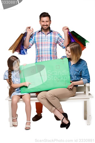 Image of Happy family with shopping bags sitting at studio 