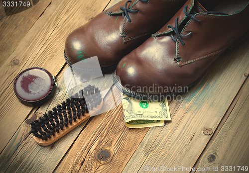 Image of boots, brush, shoe polish and dollar