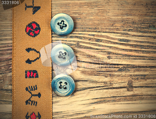 Image of vintage tape with embroidered ornaments and three old button