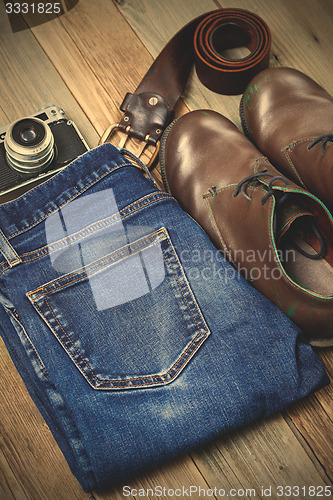 Image of brown boots, blue jeans, leather belt and rangefinder camera