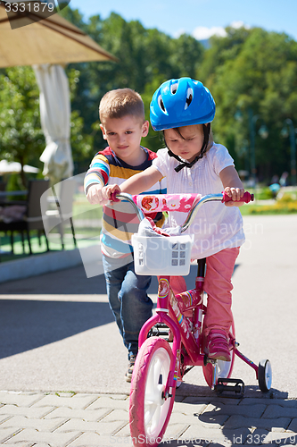 Image of Boy and girl in park learning to ride a bike