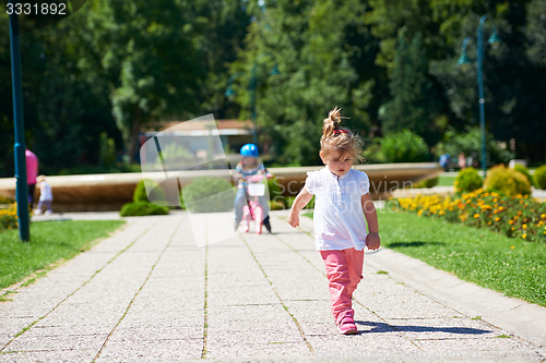 Image of Boy and girl in park learning to ride a bike