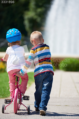 Image of Boy and girl in park learning to ride a bike