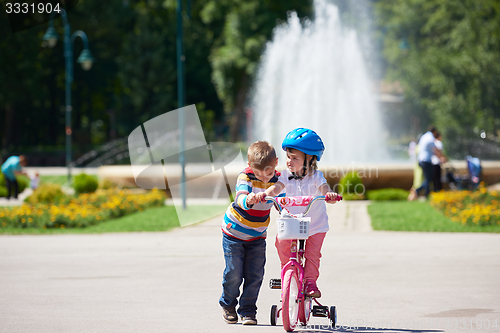 Image of Boy and girl in park learning to ride a bike