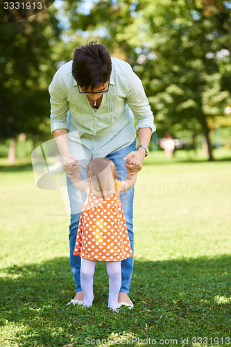 Image of mother and baby in park making first steps