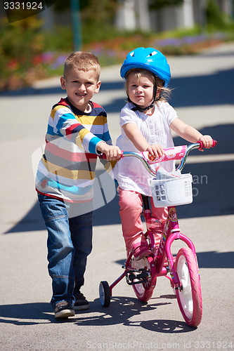 Image of Boy and girl in park learning to ride a bike