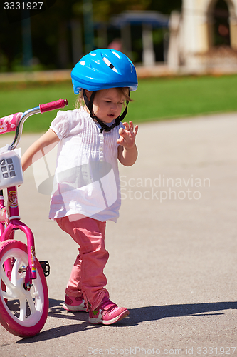 Image of Boy and girl in park learning to ride a bike