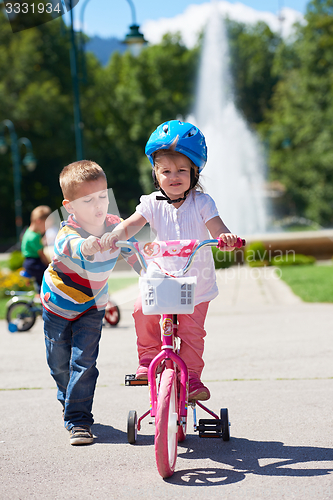 Image of Boy and girl in park learning to ride a bike
