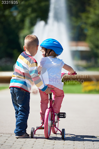 Image of Boy and girl in park learning to ride a bike