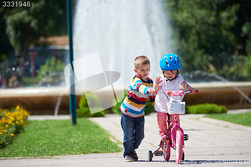 Image of Boy and girl in park learning to ride a bike