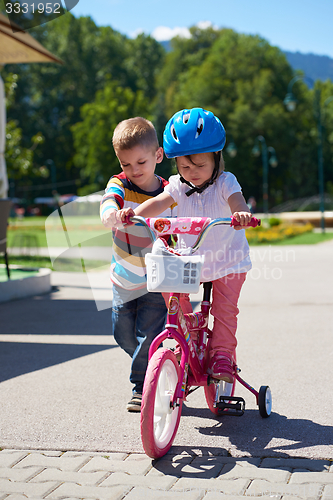 Image of Boy and girl in park learning to ride a bike