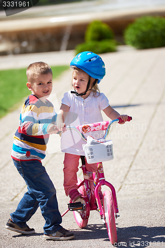 Image of Boy and girl in park learning to ride a bike
