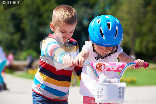 Image of Boy and girl in park learning to ride a bike