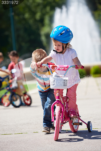Image of Boy and girl in park learning to ride a bike