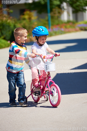 Image of Boy and girl in park learning to ride a bike