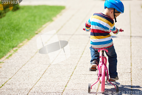 Image of happy boy learning to ride his first bike