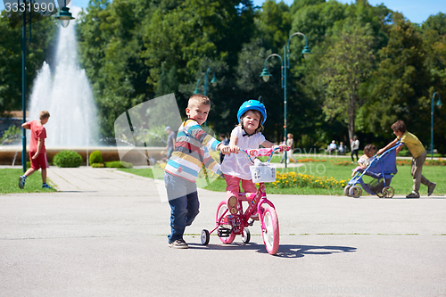 Image of Boy and girl in park learning to ride a bike