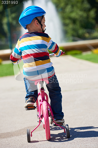 Image of happy boy learning to ride his first bike