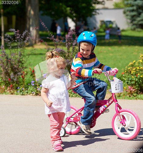 Image of Boy and girl in park learning to ride a bike
