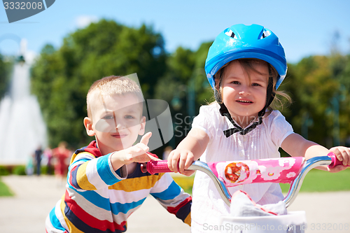 Image of Boy and girl in park learning to ride a bike