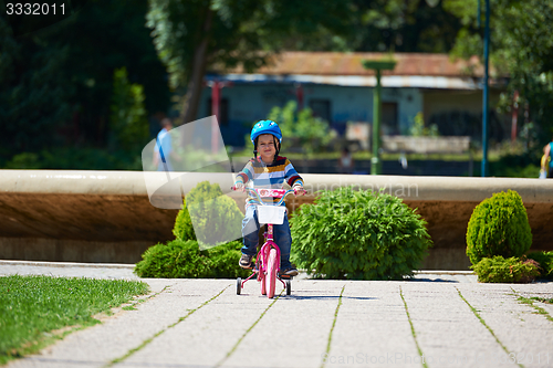 Image of happy boy learning to ride his first bike