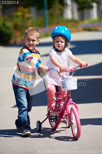 Image of Boy and girl in park learning to ride a bike