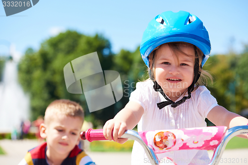 Image of Boy and girl in park learning to ride a bike