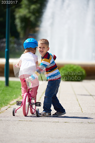 Image of Boy and girl in park learning to ride a bike