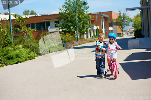 Image of Boy and girl in park learning to ride a bike