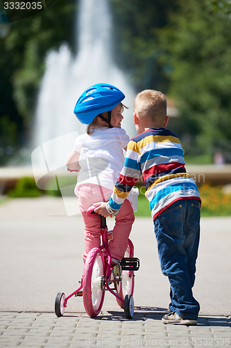 Image of Boy and girl in park learning to ride a bike