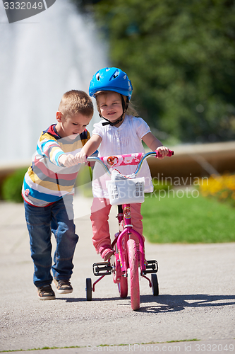 Image of Boy and girl in park learning to ride a bike
