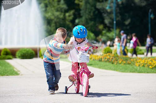 Image of Boy and girl in park learning to ride a bike