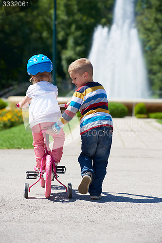 Image of Boy and girl in park learning to ride a bike