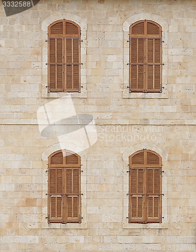 Image of Wall of the old building with closed windows covered by wooden blinds