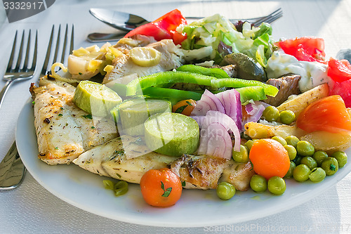 Image of Meat, fish and various vegetable garnish on a plate.