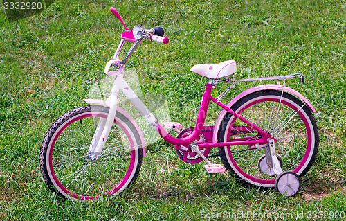 Image of The bicycle for the girl on a green lawn.