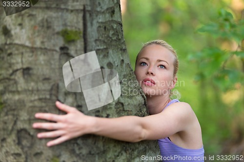 Image of Young woman hugging a tree.