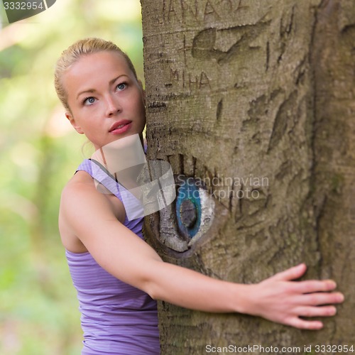 Image of Young woman hugging a tree.