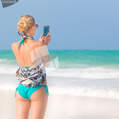 Image of Woman taking photo on the beach.