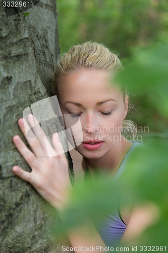 Image of Young woman hugging a tree.