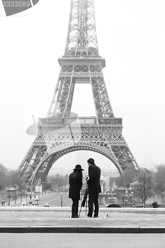 Image of Couple taking photo of Eiffel tower in Paris.