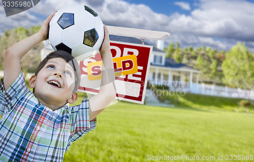 Image of Boy Holding Ball In Front of House and Sold Sign