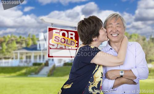 Image of Affectionate Senior Chinese Couple In Front of House and Sign