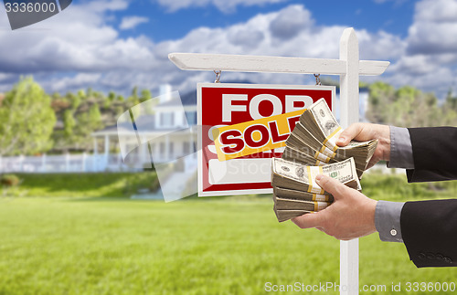 Image of Man Handing Over Money in Front Sold House and Sign