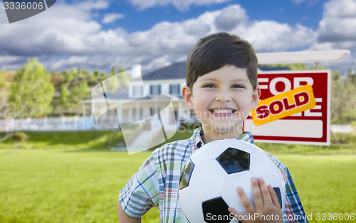 Image of Boy Holding Ball In Front of House and Sold Sign