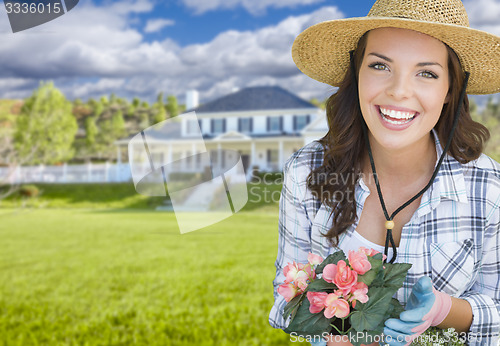 Image of Young Woman Gardening in Front of Beautiful House